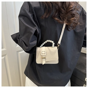 Detail of off-white mini crossbody bag with pearl handle and woven texture on model