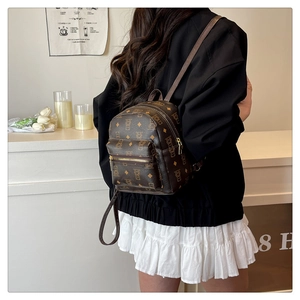 Vue arrière du mannequin portant le mini sac à dos ours marron dans un café épuré