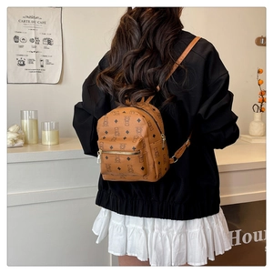 Detail eines braunen Mini-Rucksacks mit Bärenprint und Reißverschlusstasche im Café