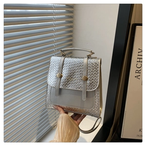 Detail of silver snake-embossed handbag with dual gold cylinders and top handle