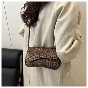 Dettaglio di borsa a tracolla leopardata su uno sfondo di trench beige classico