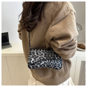 Dettaglio della borsa a tracolla leopardata indossata con un maglione in un ambiente caldo