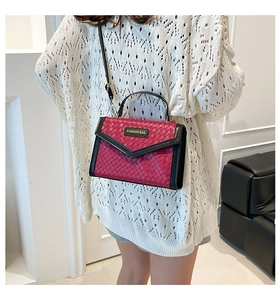 Macro view of dark red woven texture handbag with black trim and gold fashion bag logo