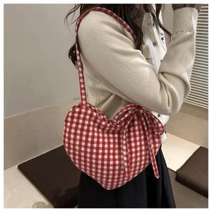 Détail du sac cabas en forme de cœur à carreaux rouge et blanc avec un nœud à l'épaule