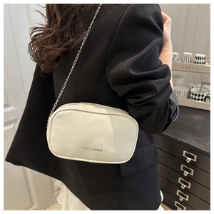 Detailed side view of white leather mini makeup bag with silver chain strap and logo