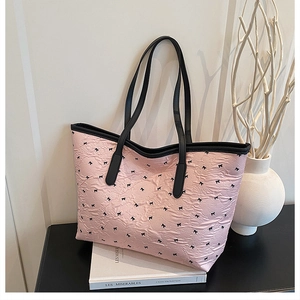 Nahaufnahme der rosa Totebag mit Schleifenprint und Faltenstruktur auf weißen Büchern