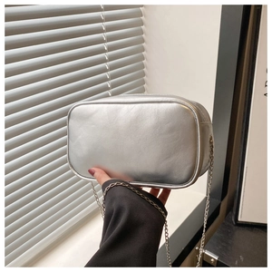 Detail showing the silver metallic chain strap and smooth faux leather surface of the bag