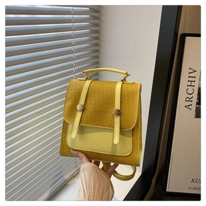 Close-up of yellow embossed leather mini backpack with textured finish and buckle detail