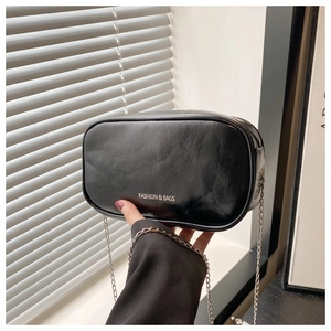 Close-up of black PU leather mini cosmetic bag with chain strap and fashion text