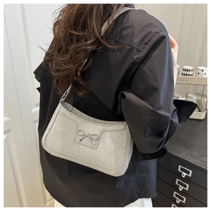 Detailed view of silver sequin shoulder bag with a stylish metallic bow decoration