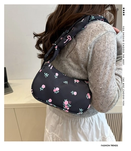 Détail du sac sous le bras noir avec motifs de roses roses et nœuds porté par un mannequin