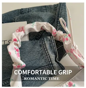 Detail of floral scrunchie handle with pink rose patterns on a soft fabric shoulder bag
