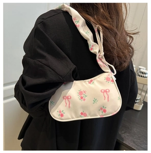 Détail du sac hobo avec imprimés de roses roses et motifs de nœuds sur l'épaule