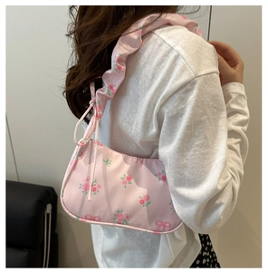 Détail du sac à bandoulière en toile florale avec motifs roses et sangle à volants