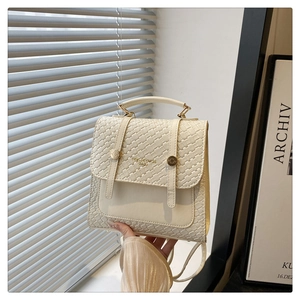 Detail of cream-colored vintage backpack with woven texture, metal handle and flap buckle