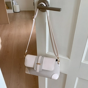 Sac baguette rétro crème avec texture tissée et bandoulière réglable sur une porte