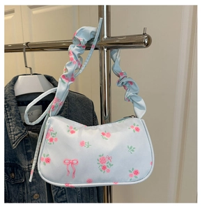 Détail du sac sous le bras bleu clair avec motifs de roses roses et bandoulière froncée