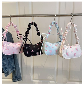 Détail de sacs sous le bras floraux en rose, noir, bleu et blanc avec nœuds