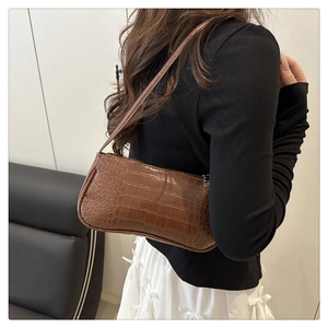 Brown crocodile pattern faux leather baguette bag worn over the shoulder by a model