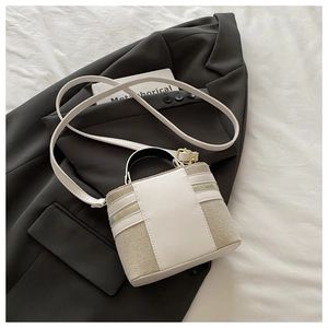 Detailed macro view of beige woven fabric and white leather trim on a mini bucket bag