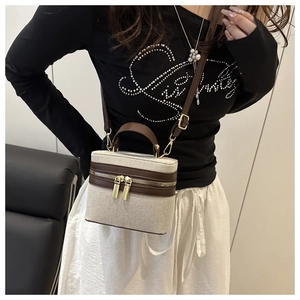 Detail view of contrast stitching canvas and leather vanity bag on model shoulder