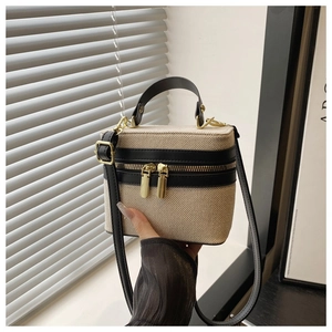 Detail showing dual metal zippers and canvas texture on bicolor small square handbag