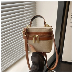 Detail of a retro cream canvas box bag with brown leather trim and dual zippers