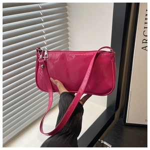 Close-up of glossy rose red patent leather baguette bag with silver metal zipper detail