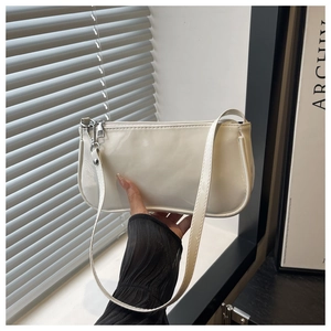Close-up of white glossy patent leather baguette bag with silver zipper and slim strap