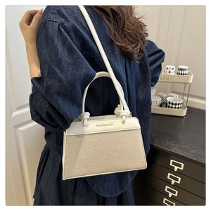 Side view of beige canvas and white leather handbag worn as a stylish crossbody bag