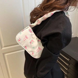 Sac sous le bras blanc style japonais avec motifs roses et nœuds porté par modèle
