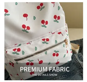 Detail of red cherry print on white polyester backpack with gold metal zipper closure