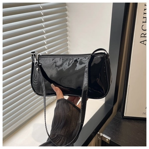 Detail of glossy black patent leather shoulder bag with smooth surface and zipper closure