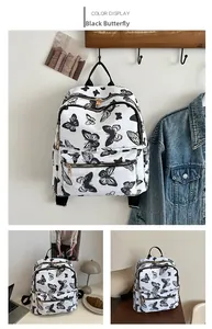 Detail view of large capacity white backpack with black butterfly print and gold zippers