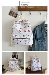 Detail of white nylon backpack featuring all-over cherry print and metal zipper pocket