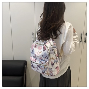 Detail view of large butterfly print backpack featuring multiple zipper pockets on model