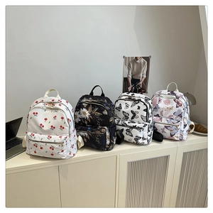 Macro detail of four canvas backpacks with cherry, floral, and butterfly printed patterns