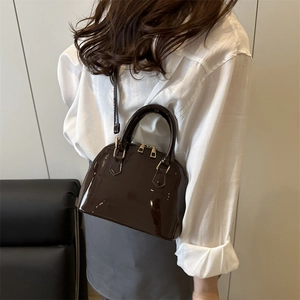 Glossy dark brown shell-shaped crossbody bag with gold hardware and twin handles