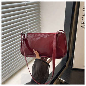 Detail of burgundy patent leather baguette bag with silver zipper and glossy finish