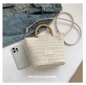 Detail of hand-woven straw bucket bag with wooden handle and slim shoulder strap