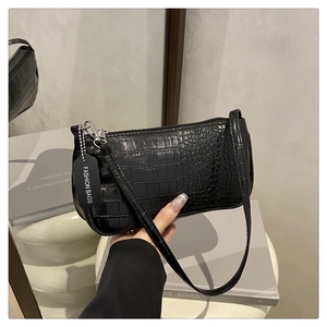 Close-up of black crocodile pattern faux leather baguette bag with a metal zipper