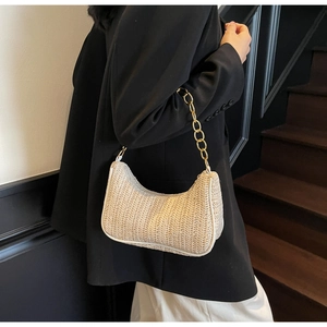Detail of beige woven hobo bag with a V-pattern texture and chunky gold chain strap