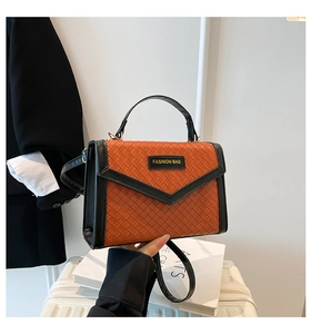 Detail of orange woven texture and black leather contrast on a luxury small square handbag