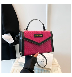 Detail of woven texture handbag with black trim and V-shaped flap in magenta pink
