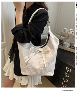 Detail of white woven leather tote bag with a slim bow and textured geometric pattern