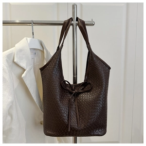 Detail of deep brown woven hobo bag featuring a stylish leather bow tie accent