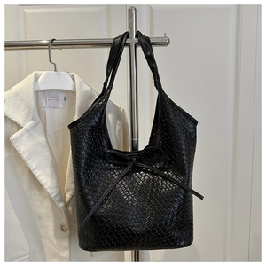 Detail of black woven tote bag with a delicate bow knot and textured finish