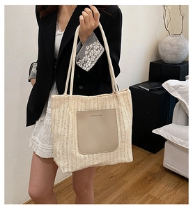 Detail of beige woven tote bag with a front PU leather pocket and long shoulder straps