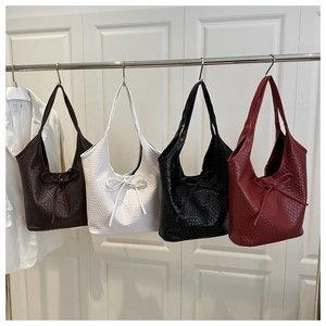 Detail view of woven texture and bow accent on tote bags in four classic colors
