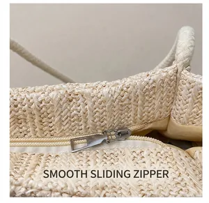 Detail showing smooth silver metal zipper and woven texture on large straw bag